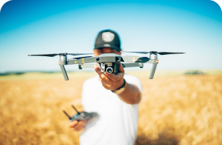 A man holding a drone in a field, ready for flight.